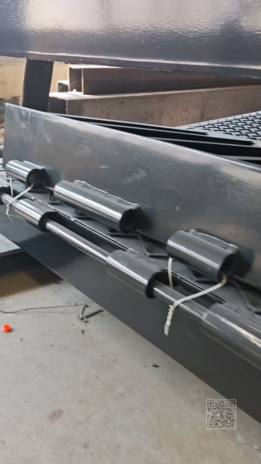 Close-up of steel tail plate hinge assemblies on a mobile dock ramp during fabrication