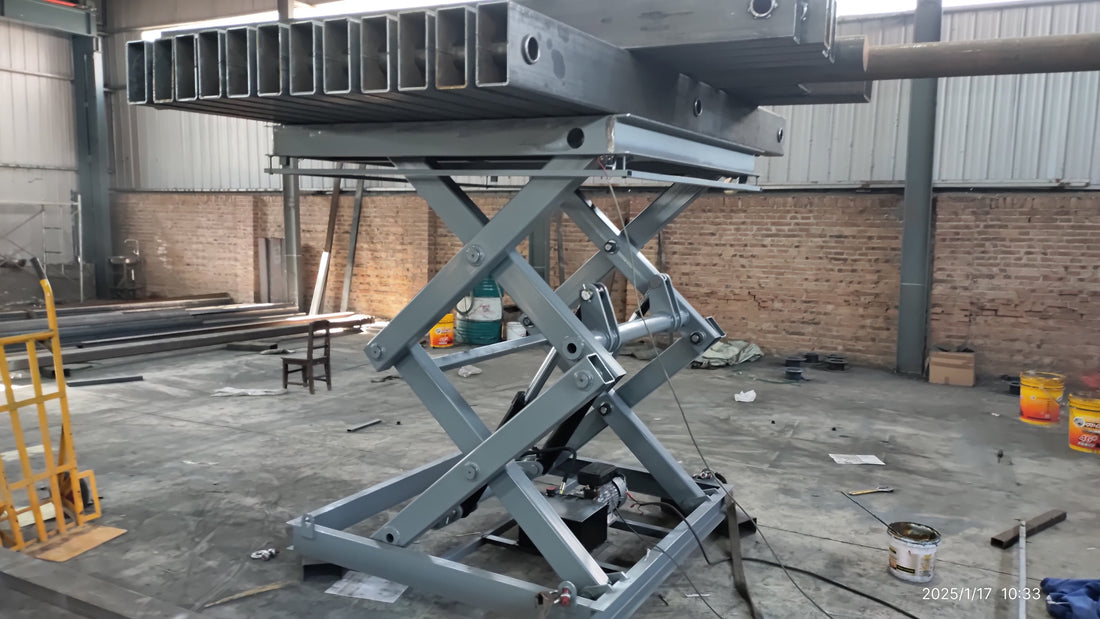 Raised stationary hydraulic scissor lift supporting rectangular steel tubes during a factory load test.