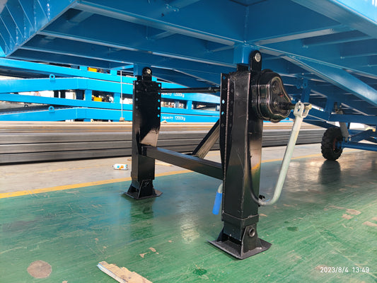 Two black auxiliary support legs with square footplates and a hand crank beneath a blue mobile dock ramp frame