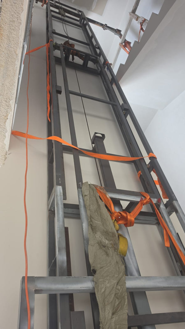 3-floor home lift frame installation in progress, showing upper guide rail section being lifted into position