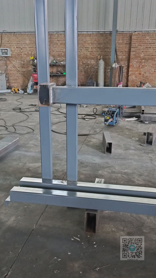 Worker welding hydraulic cylinder mounting base onto guide rail lift structure at Beacon Industries